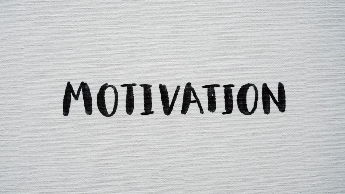 Inspirational word 'Motivation' in black on a white textured canvas background.
